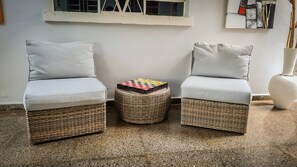 Relax in a comfortable seating area with two cushioned chairs and a wicker ottoman.