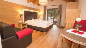 A bedroom with a bed, a sofa, a table, and a window. - Moseralm Dolomiti Hideaway (Nova Levante)