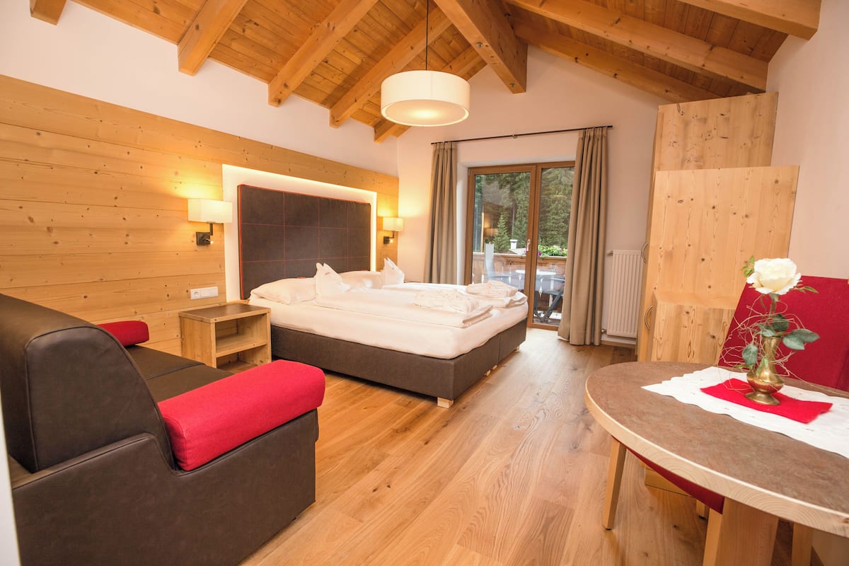 A bedroom with a bed, a sofa, a table, and a window.