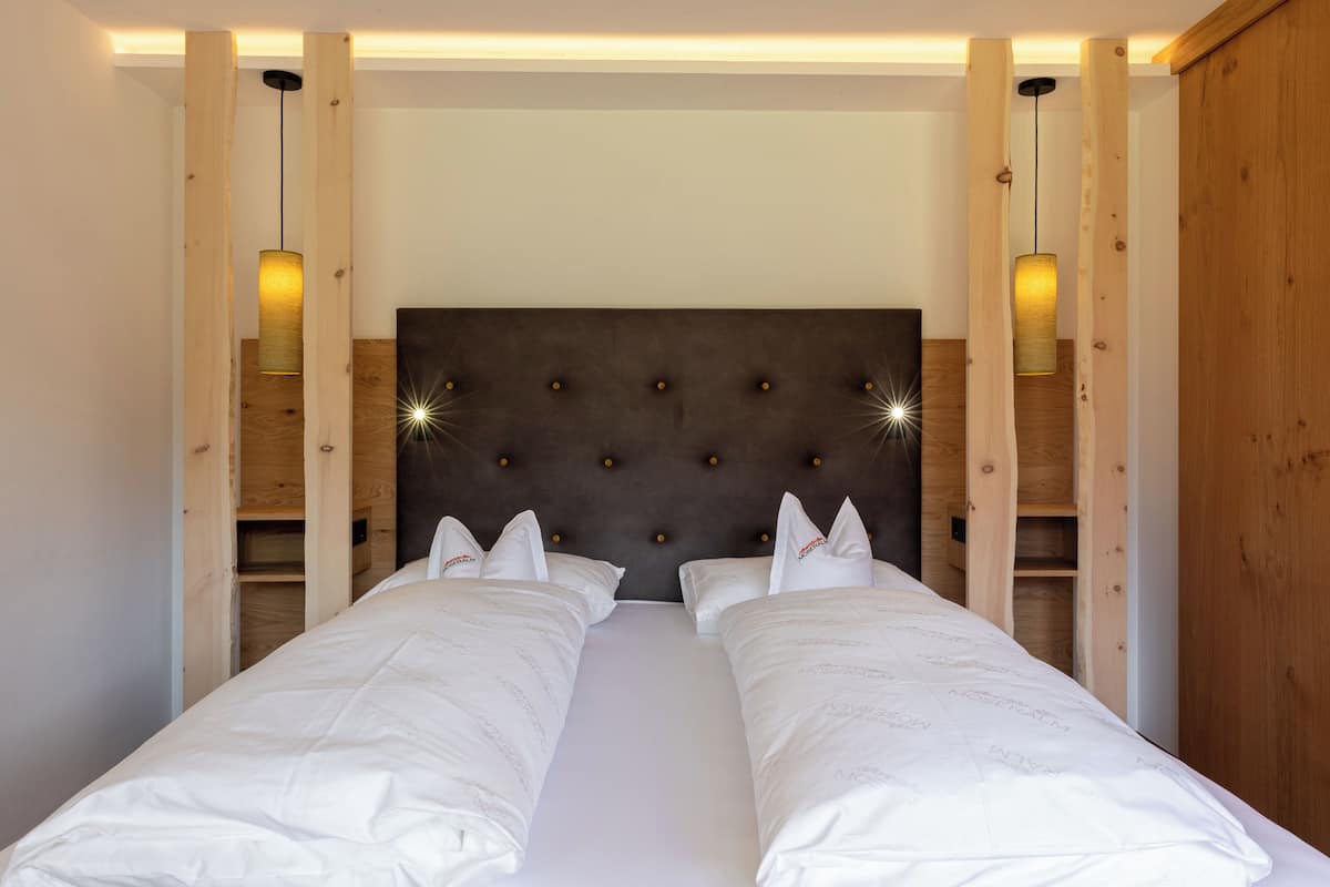A double bed with a tufted headboard, two bedside tables, and wall-mounted lamps.