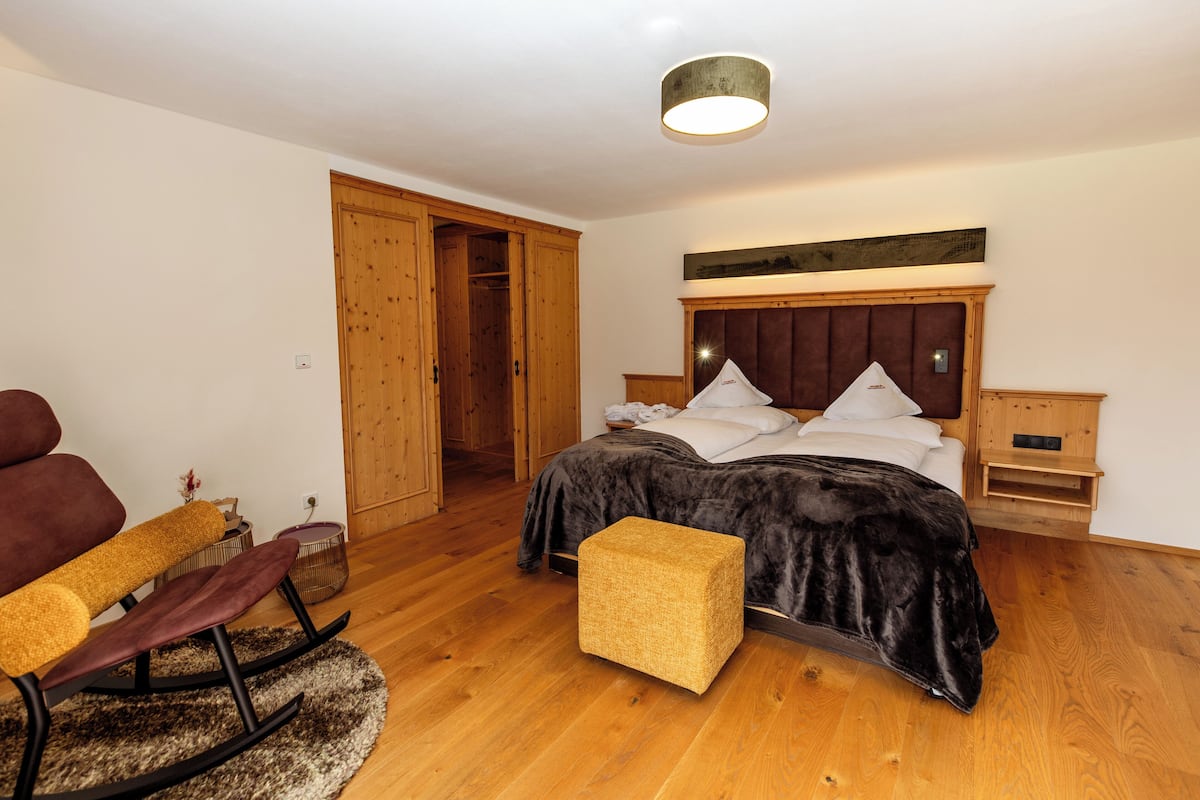 A bedroom with a bed, wooden wardrobe, and a rocking chair.