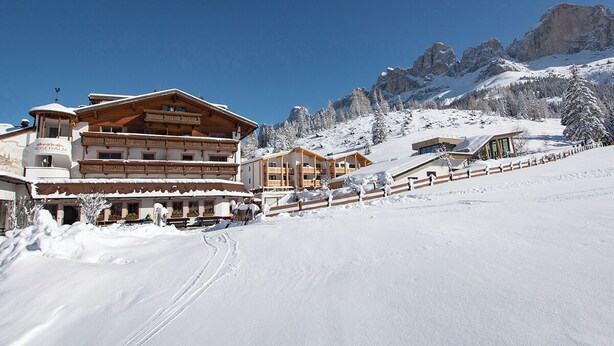 A snow-covered ski resort with wooden buildings and a clear blue sky. - Moseralm Dolomiti Hideaway (Nova Levante)
