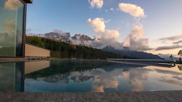 Una piscina techada, una piscina al aire libre, sombrillas