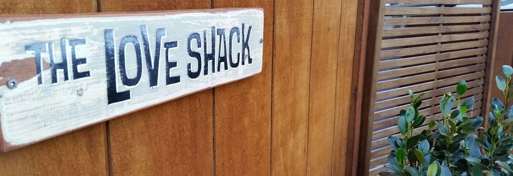 A wooden wall with a sign that reads "THE LOVE SHACK".