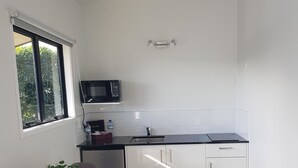 Une cuisine compacte avec des meubles blancs, un four à micro-ondes, un évier et un petit coin repas comprenant une table et des chaises.