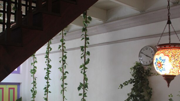 A staircase with wooden railings, a hanging plant, a wall-mounted clock, and a hanging lantern. - Secret Garden Homestay (George Town)