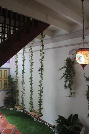 Un escalier avec des rampes en bois, une plante suspendue, une horloge murale et une lanterne suspendue.