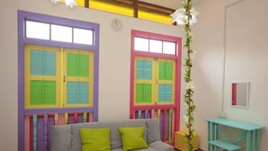 A room with a grey sofa, two green cushions, a teal side table, and a mirror. - Secret Garden Homestay (George Town)