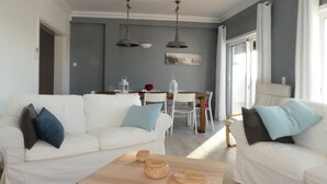 Ein modernes Wohnzimmer mit zwei weißen Sofas, einem Holztisch und einem Essbereich mit Tisch und Stühlen.