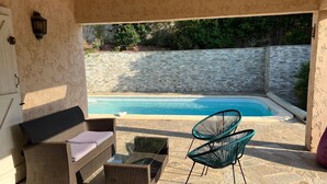 A patio with wicker furniture, a glass-top table, and a pool in the background. - The ideal place to relax, Beautiful villa with all the comforts (Sainte-Lucie de Porto-Vecchio)