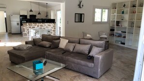 A modern living room with a sectional sofa, a glass coffee table, and a kitchen in the background. - The ideal place to relax, Beautiful villa with all the comforts (Sainte-Lucie de Porto-Vecchio)