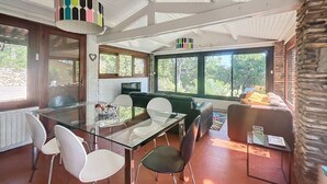 A modern dining area with a glass table, white and black chairs, and a stone accent wall. - House near Fréjus, 850 m² garden in a private gated community with a pool, tennis court, etc. (Fréjus)