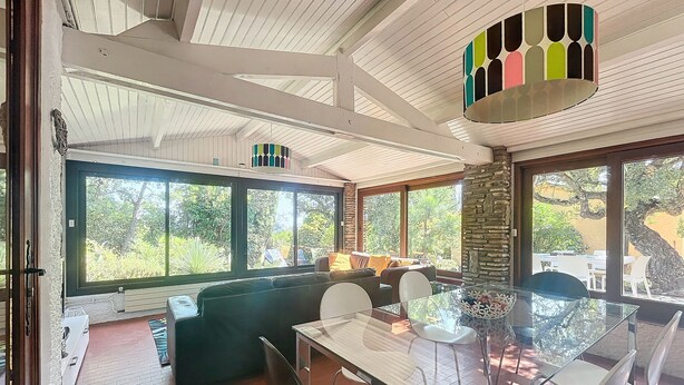 A spacious room with a large window, a glass dining table, and a comfortable seating area. - House near Fréjus, 850 m² garden in a private gated community with a pool, tennis court, etc. (Fréjus)