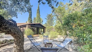 A patio with two lounge chairs and a table, surrounded by gravel and greenery, with a building in the background. - House near Fréjus, 850 m² garden in a private gated community with a pool, tennis court, etc. (Fréjus)