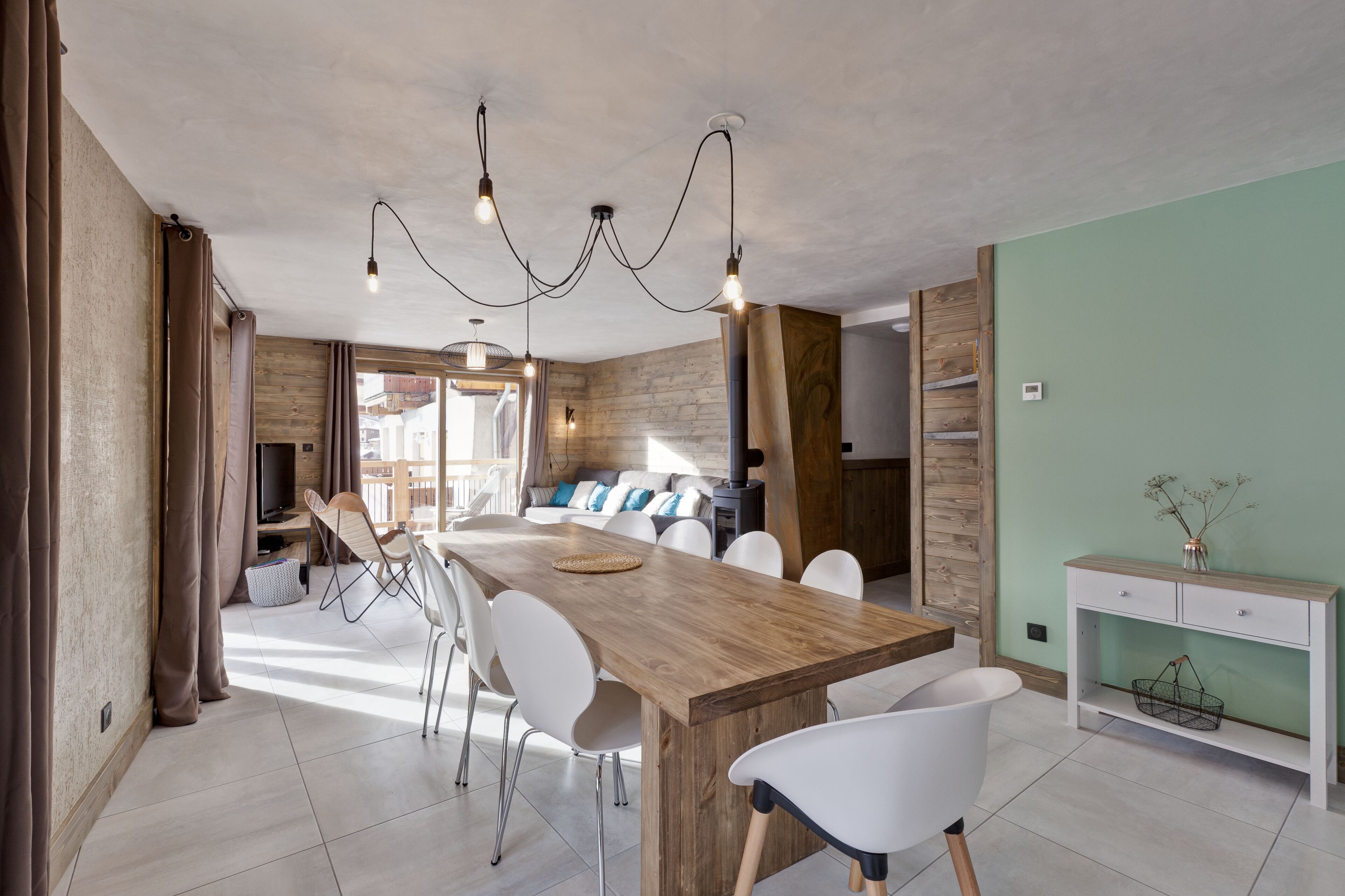 Eine moderne Küche mit einer Holztheke, weißen Stühlen und einer Pendelleuchte.
