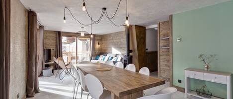 Eine moderne Küche mit einer Holztheke, weißen Stühlen und einer Pendelleuchte.