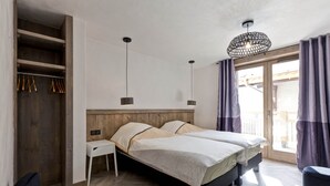 A modern bedroom with a wooden wardrobe, two beds, a desk, and a chair.