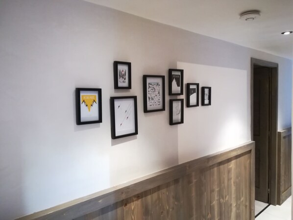 A hallway with a series of framed artworks on the wall. - Lodge 10 p. close to slopes and shops beautiful view (Champagny-en-Vanoise)