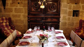 A long dining table set with purple plates, wine glasses, and a bottle of wine, surrounded by upholstered chairs. -  A privileged vacation out of time, Be the Châtelains of the Manor.     (Birac-sur-Trec)