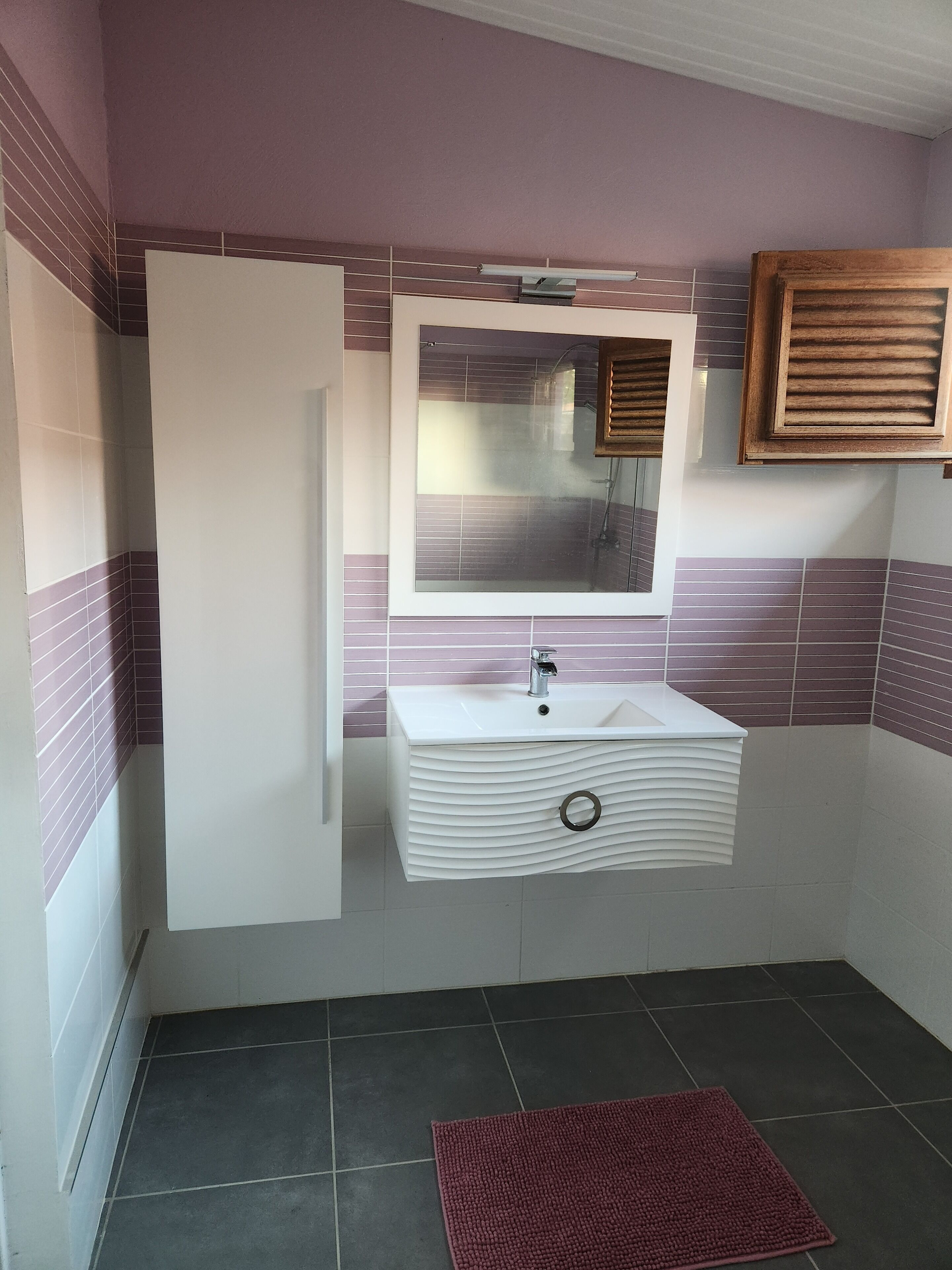 A bathroom with a white sink, a mirror, and a wooden cabinet.