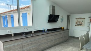A modern kitchen with a large window, built-in sink, and a flat-screen TV mounted above the counter.