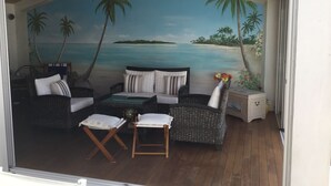 A cozy outdoor seating area with wicker furniture and a view of a beach scene.