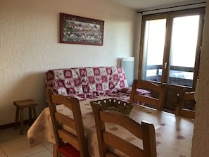 Ein Essbereich mit Holztisch, Stühlen, einer gemusterten Couch und einem Bild an der Wand.
