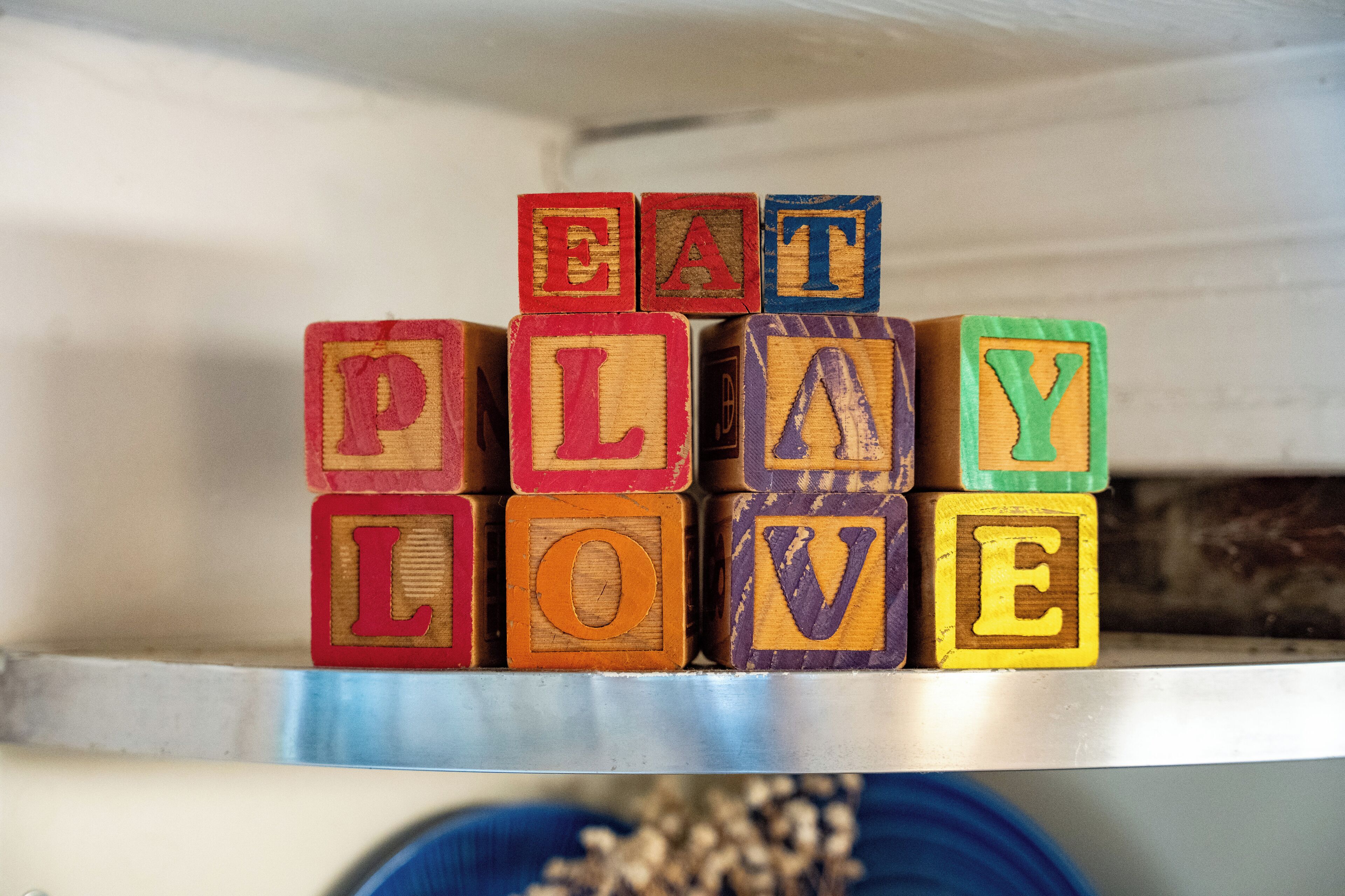 Wooden blocks spelling out "EAT PLAY LOVE" on a shelf.