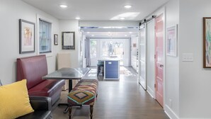 Un interior moderno con zona de comedor, una banca y cocina visible a través de una puerta abierta.