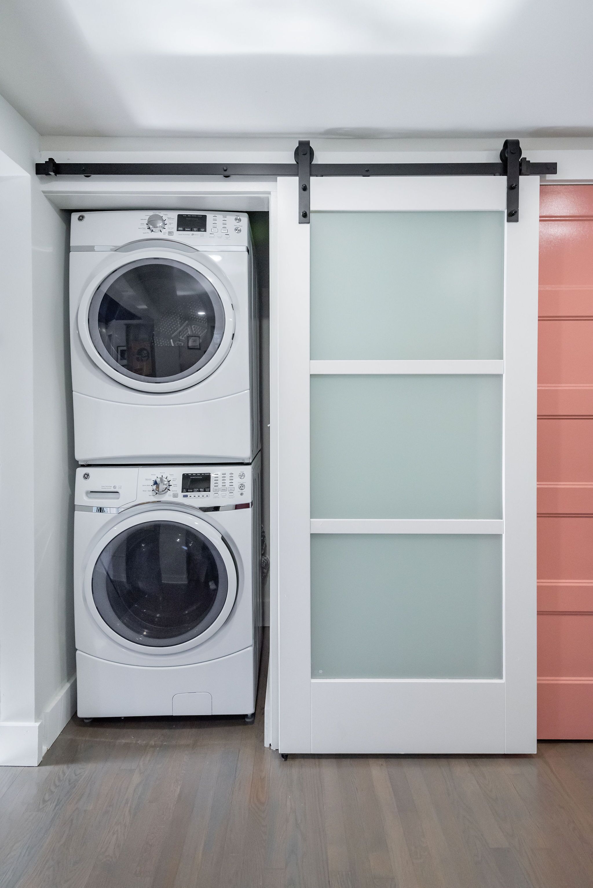 A laundry room with two stacked front-loading washing machines and a sliding door.