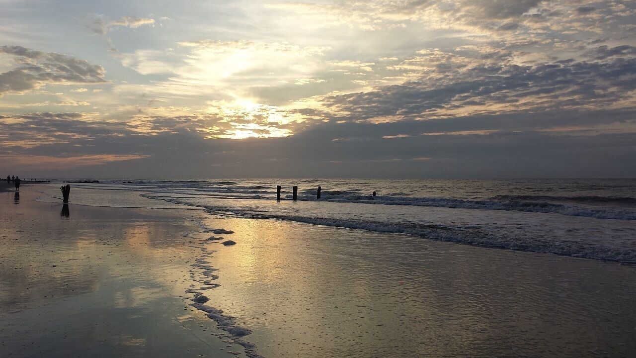 A beach with calm waves and a sunset.