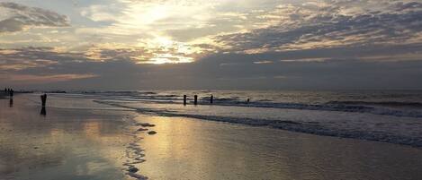 A beach with calm waves and a sunset.