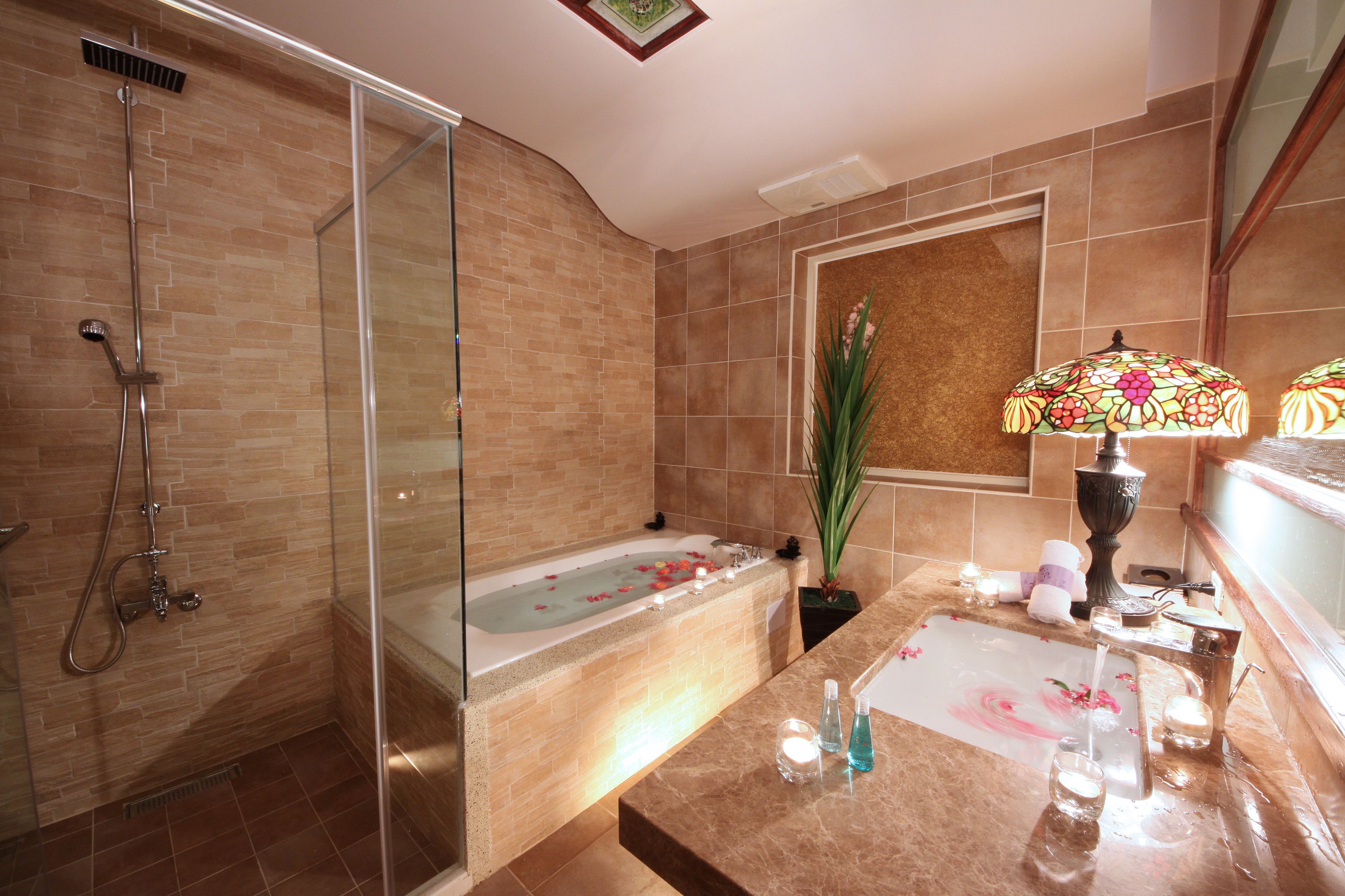 Un baño moderno con ducha envuelta en vidrio, bañera independiente y tocador con espejo.