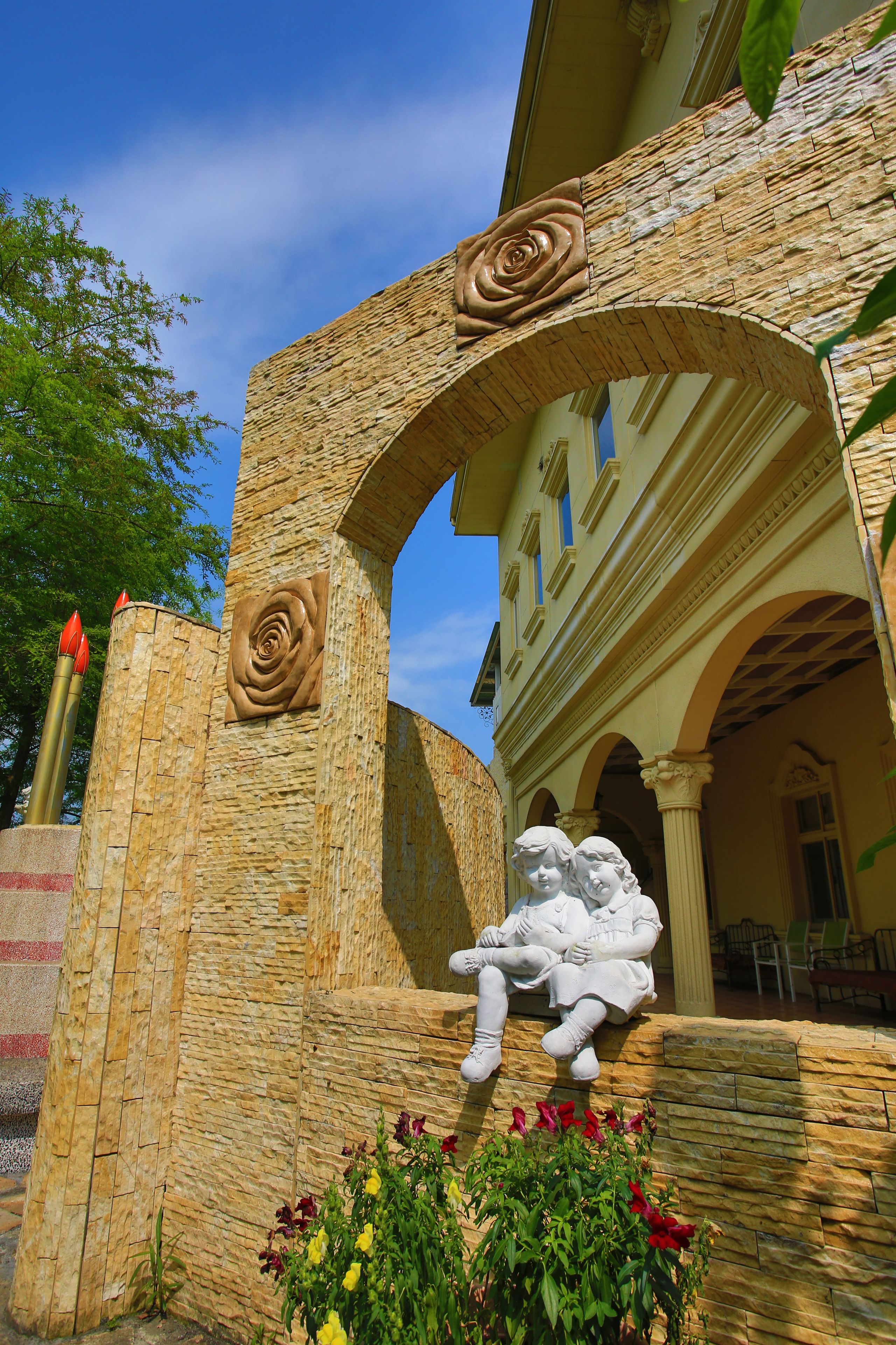 A stone archway with a rose relief and a statue of a reclining figure.