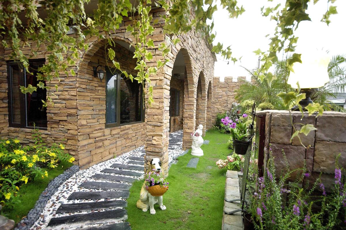 A stone building with arched windows and a paved pathway leading to a white statue.