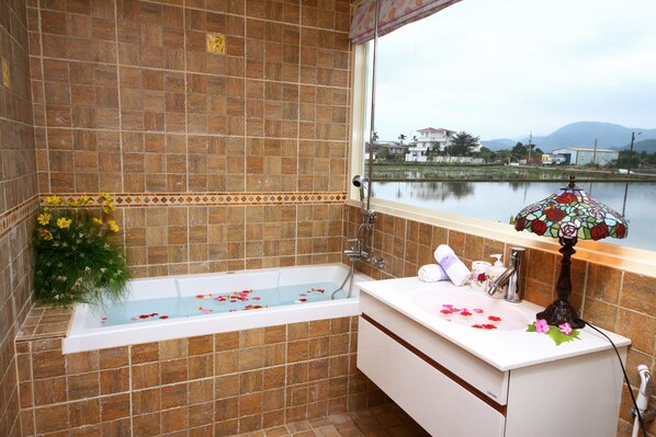 A bathroom with a bathtub, a sink, and a window overlooking a body of water. - My Dream Castle (Dongshan)