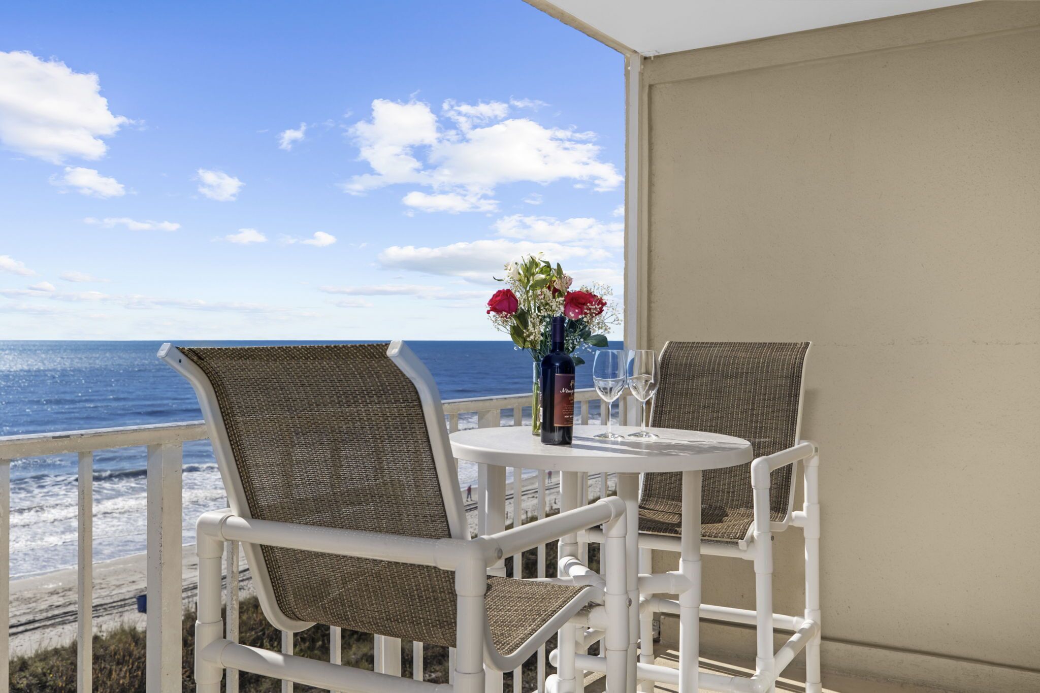 Un balcon avec des fauteuils et une table en osier, donnant sur l’océan.