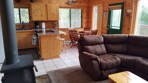 Ein gemütliches Blockhaus-Interieur mit einer Küche, einem Essbereich und einem Ledersofa.