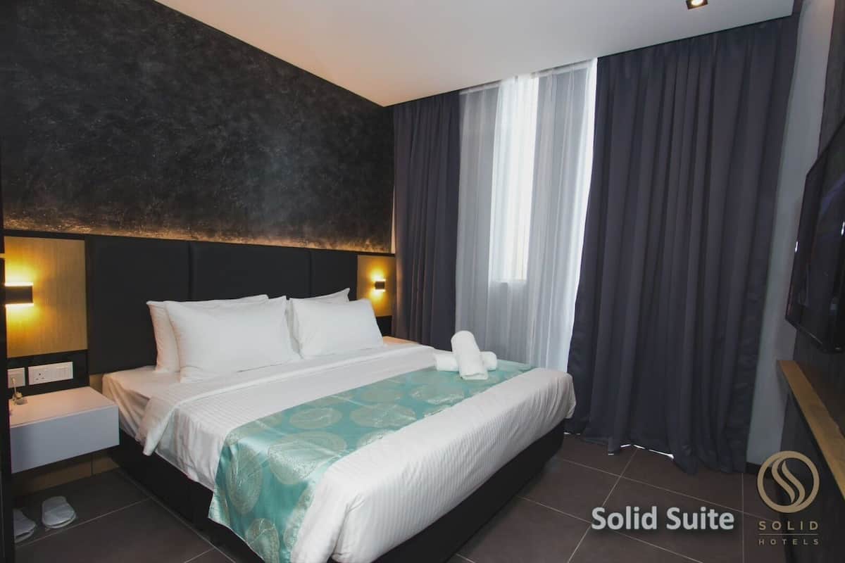 A hotel room with a large bed, a nightstand, a TV, and a view of the outdoors through the window.