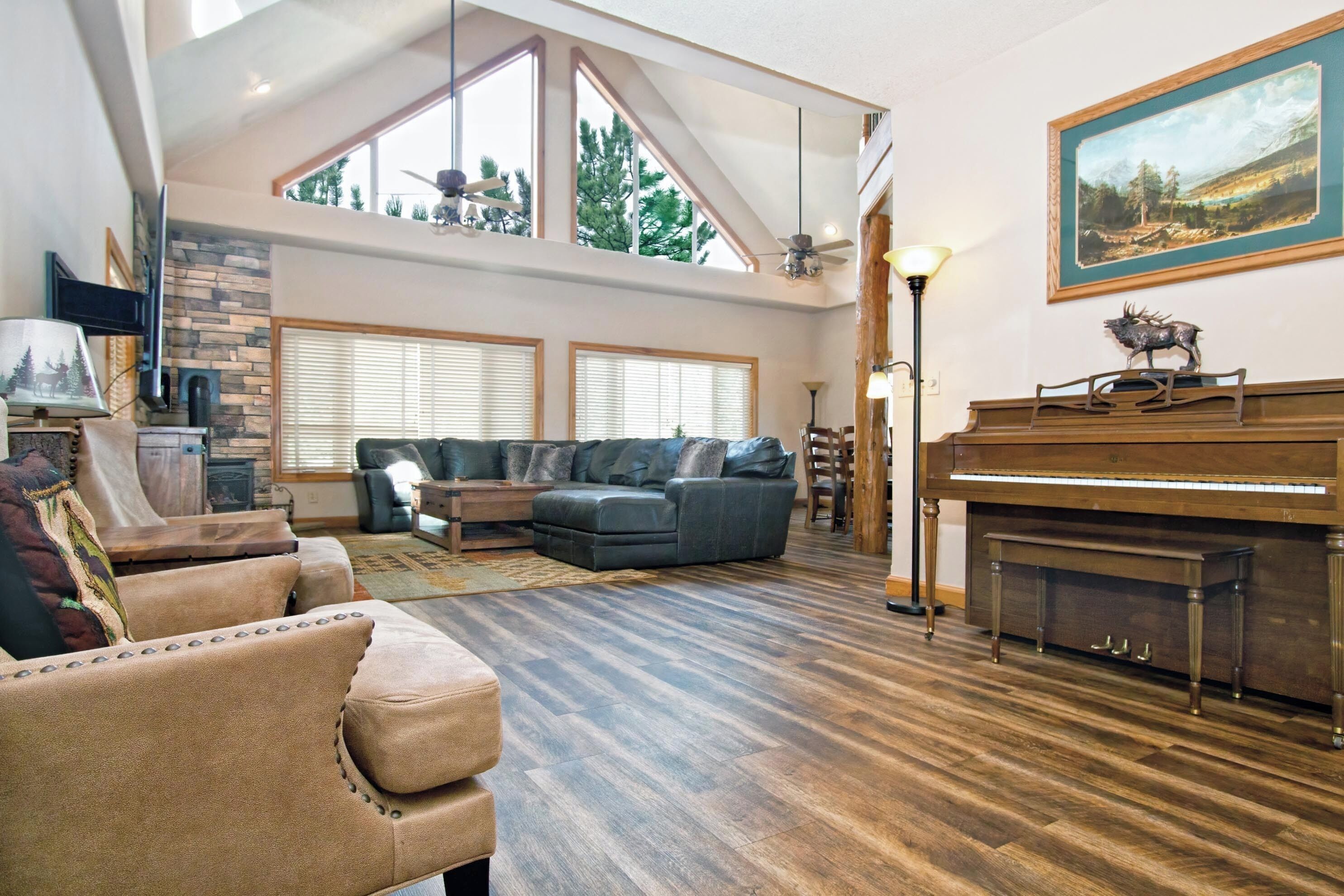 A spacious living room with a sectional sofa, a piano, and a fireplace.