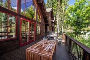 Une terrasse en bois avec une table et des bancs, donnant sur une zone boisée.