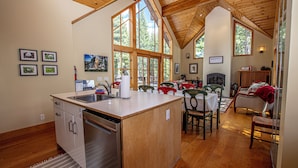 A spacious kitchen with a central island, wooden ceiling, and large windows.