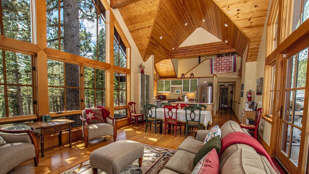 A spacious living room with a high ceiling, large windows, and a cozy seating area.