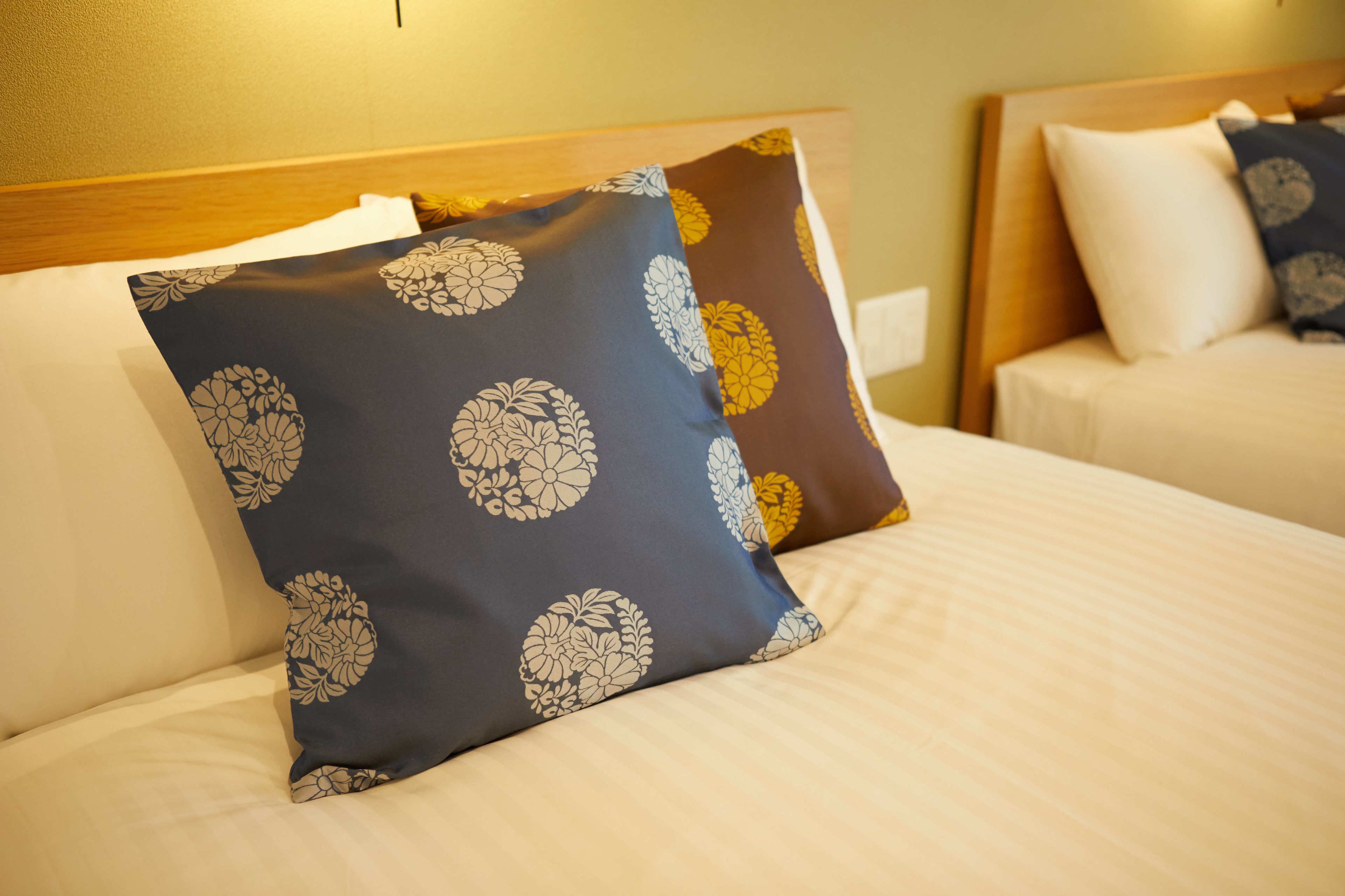 A hotel room with a neatly made bed, a wooden headboard, and a pillow with a floral pattern.