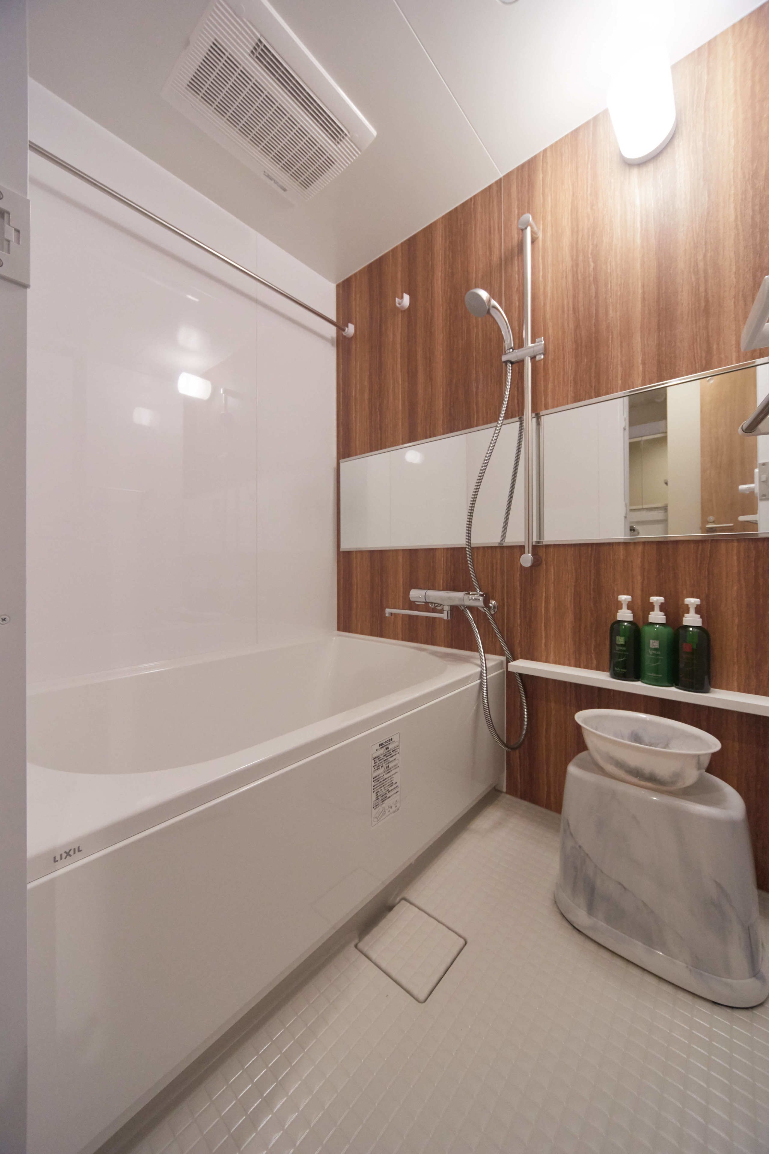 Une salle de bain moderne avec une baignoire blanche, un lambris en bois, un miroir et une étagère contenant des articles de toilette.