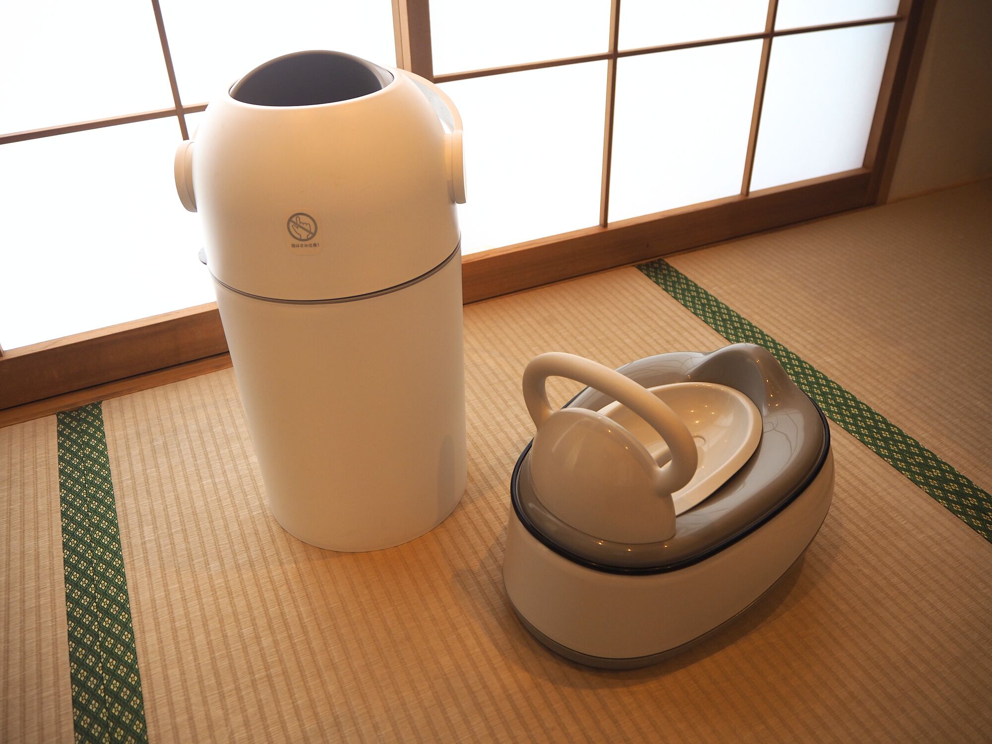 Une pièce de style japonais traditionnel, avec un sol recouvert de tatamis, un paravent en papier de riz (shoji) et un radiateur électrique blanc.