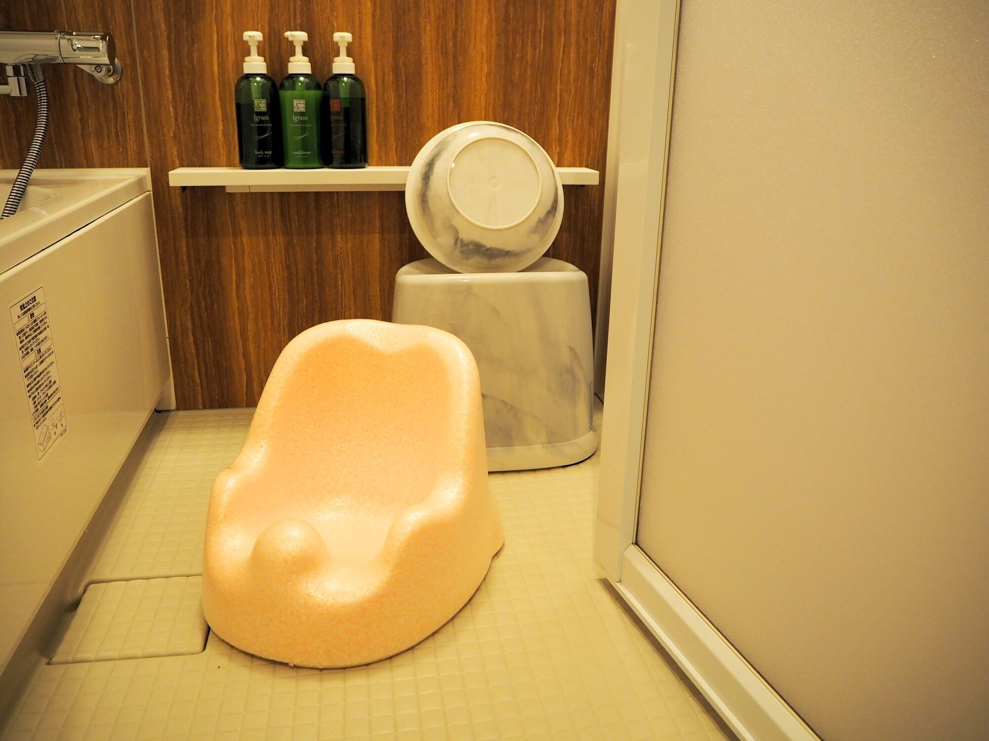Ein Badezimmer mit einer weißen Badewanne, einer weißen Toilette und einem weißen Waschbecken. Über der Toilette befinden sich drei grüne Flaschen auf einem Regal.