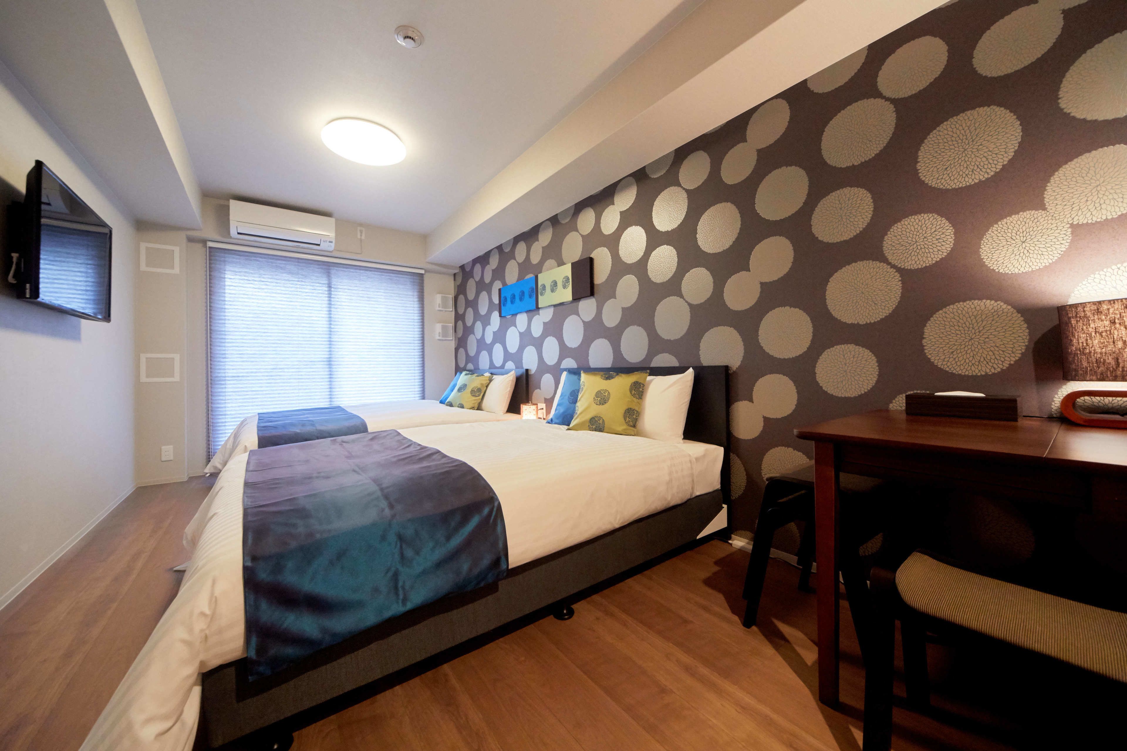 A bedroom with a bed, a desk, and a wall with a polka dot pattern.
