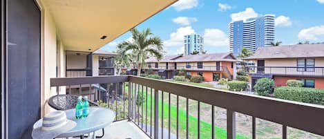 A balcony with a table, two chairs, and two bottles of water.