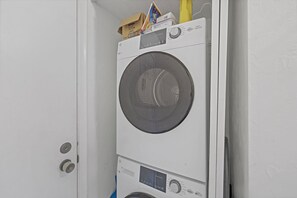 A stacked washer and dryer unit in a room with a white door and wall.